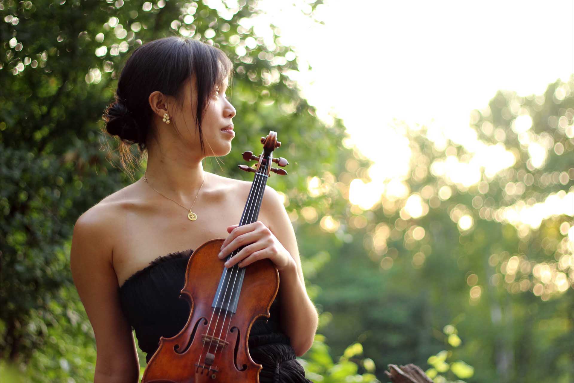 woman outdoors, holding a violin